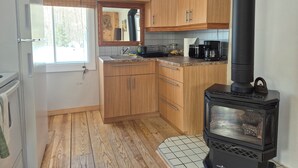 Una cocina con armarios de madera, una estufa negra y una ventana.