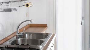 A kitchen with a gas stove, stainless steel sink, and wooden cabinets. - Apartment With sea View Balcony (Jesolo)
