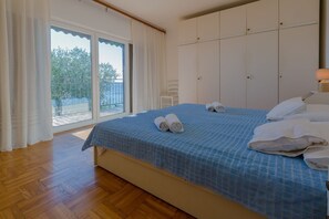A bedroom with a bed, a nightstand, a lamp, and a view of the outdoors through a sliding door. - Fantastic apartment right by the sea with parking space, sea view, washing machine (Crikvenica)