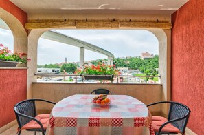 A balcony with a table and chairs, a view of a bridge, and a cityscape in the background. - Cosy apartment just 500 metres from the beach with private parking, air conditioning and WiFi (Crikvenica)