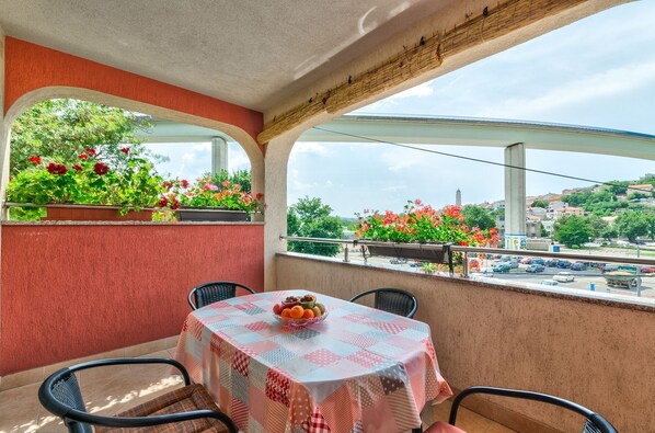 A balcony with a table and chairs, a view of a cityscape, and potted plants with flowers. - Cosy apartment just 500 metres from the beach with private parking, air conditioning and WiFi (Crikvenica)