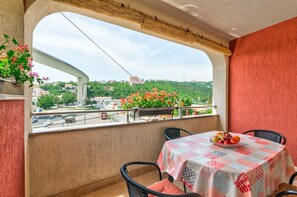A balcony with a table set for dining, overlooking a cityscape with a bridge and greenery. - Cosy apartment just 500 metres from the beach with private parking, air conditioning and WiFi (Crikvenica)
