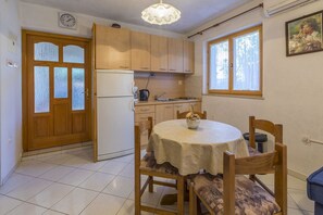 A compact kitchen with wooden cabinets, a refrigerator, a sink, and a dining table with chairs. - Romantic studio apartment just 410 metres from the beach with private parking space (Selce)