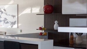 A modern kitchen with a white countertop, a red apple, a pineapple-shaped vase, and a fruit stand with various fruits. - Charming apartment with pool, sea view, garage, washing machine (Klenovica)