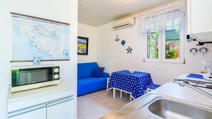 Une cuisine de taille réduite, équipée d’un évier, d’un four à micro-ondes et d’une table recouverte d’une nappe bleue.