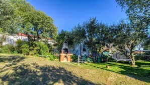 Un jardin agrémenté d’une cheminée extérieure en briques, entouré d’une végétation luxuriante et d’un hamac.