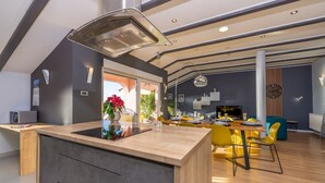 Una cocina moderna con una isla central, un comedor con sillas amarillas y un amplio ventanal que proporciona luz natural.