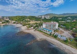 Ein Küstenhotel mit Blick auf den Strand, mehreren Etagen und einem Poolbereich.