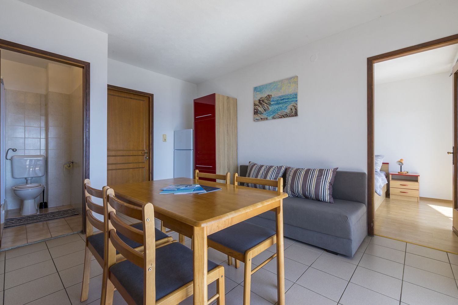 A compact living space with a dining table, sofa, and a painting on the wall.