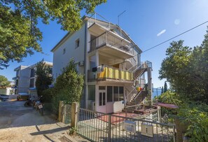 Ein mehrstöckiges Gebäude mit Balkonen, einer Treppe und Blick aufs Meer.