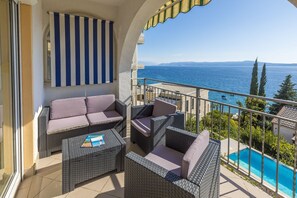 Ein Balkon mit Korbmöbeln und Blick auf das Meer.