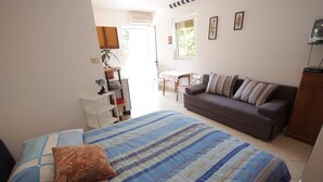 Ein Schlafzimmer mit Bett, Sofa, kleinem Tisch und Fernseher.