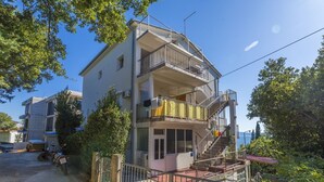 Ein mehrstöckiges Gebäude mit Balkonen, einer Treppe und Blick aufs Meer.