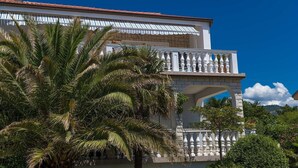 A building with a white facade, a red-tiled roof, and a balcony with white balustrades. - Idyllic apartment with pool, table tennis, summer kitchen, private parking (Crikvenica)