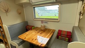 Interni camper compatti con un tavolo di legno, sedute imbottite, una finestra vista e un cartello 'No Smoking'.