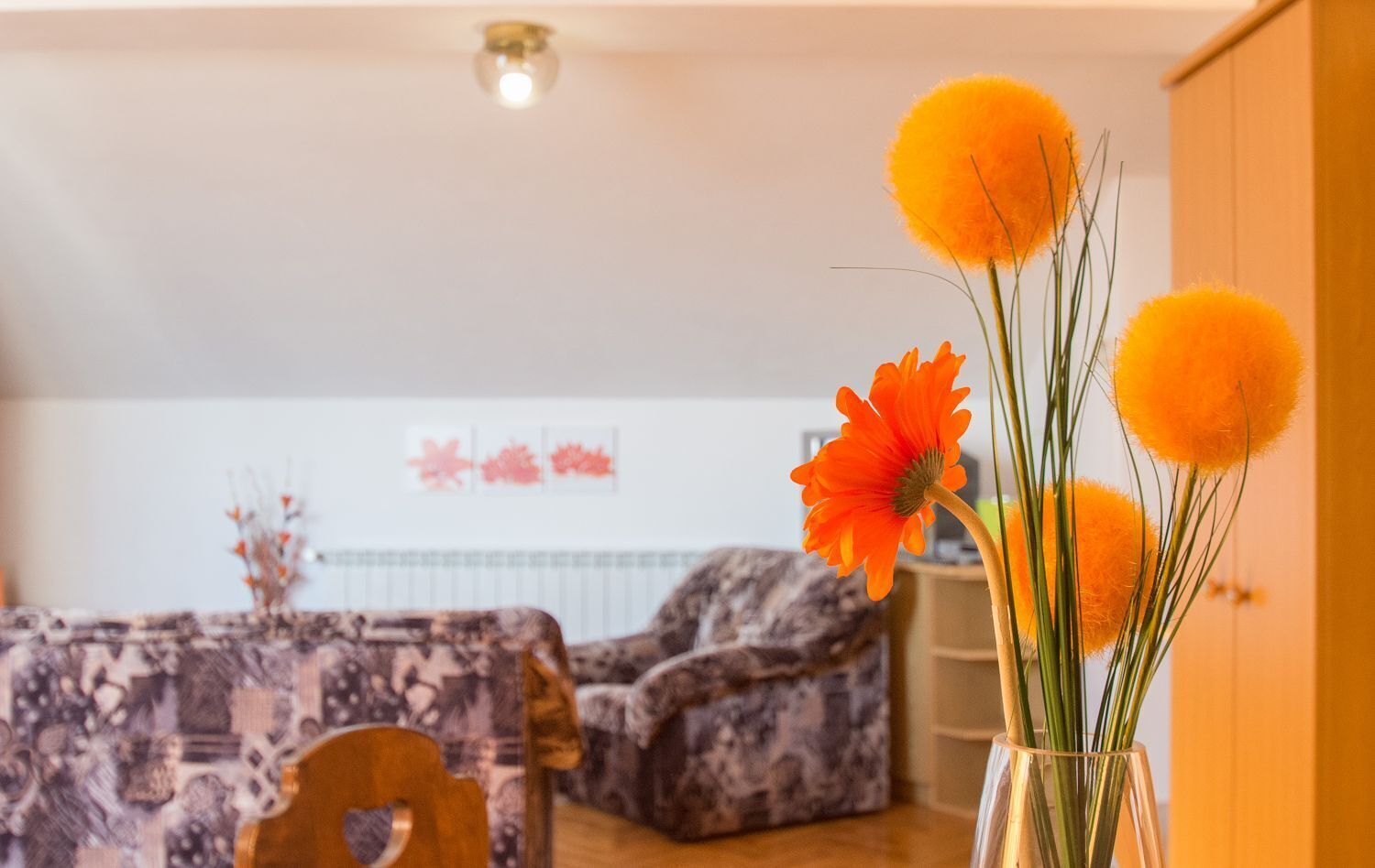Un salon avec un canapé à motifs, une table basse et un vase rempli de fleurs oranges.