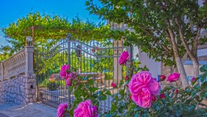 Eine Steinsäule, ein Metallgitter und rosa Rosen.