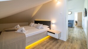 Un dormitorio moderno con techo inclinado, una cama con ropa de cama blanca, una mesita de noche y una lámpara de noche.