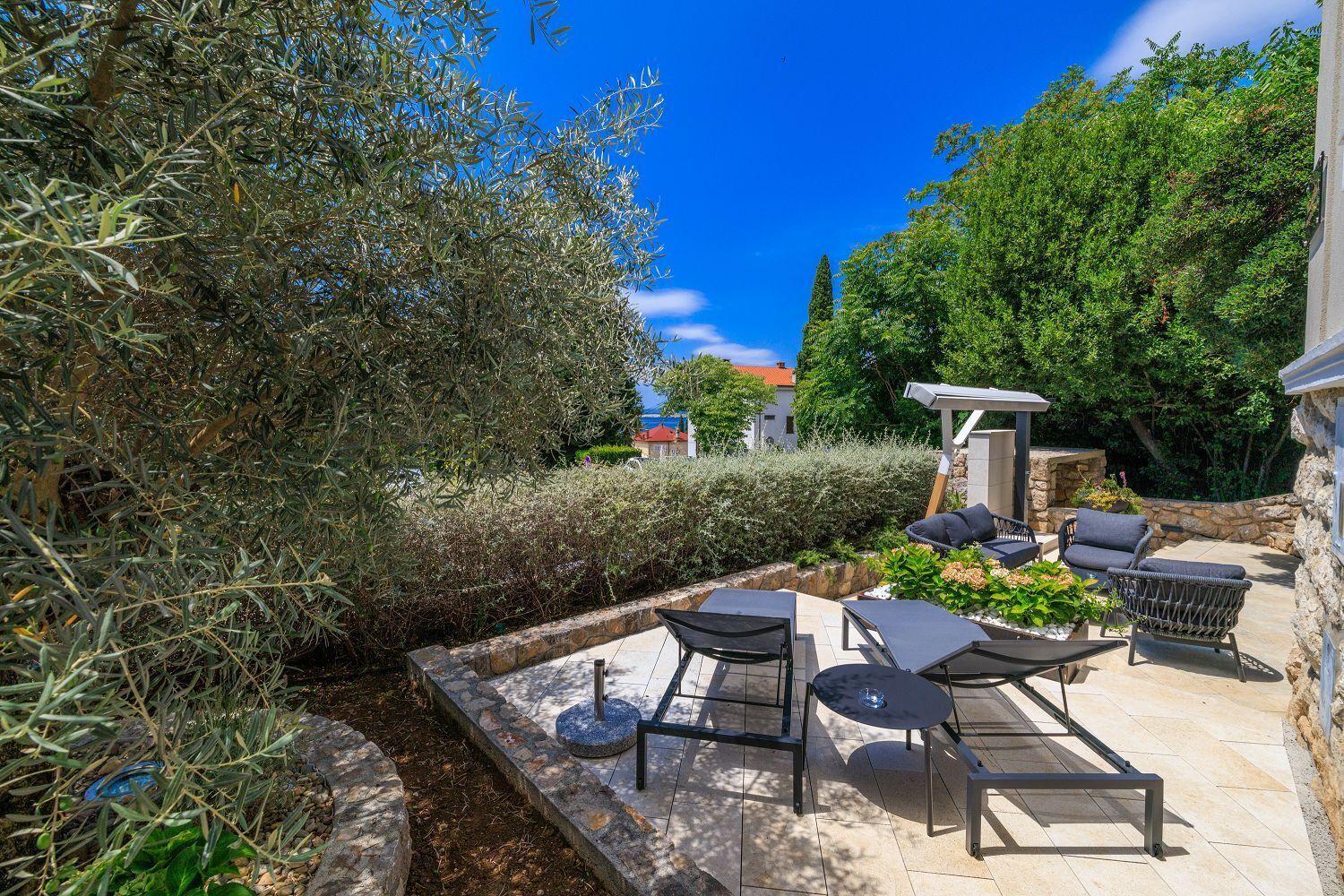An outdoor patio with stone flooring, a pergola, and outdoor furniture.