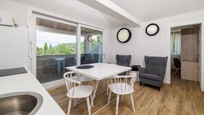 Una cocina moderna con comedor, un sofá gris y vista a la vegetación a través de una puerta corrediza de vidrio.