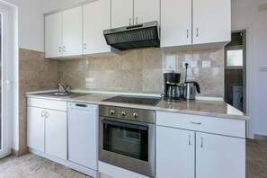 A modern kitchen with white cabinets, a stainless steel oven, a dishwasher, a coffee maker, and a built-in microwave. - Bright apartment just 300 metres from the beach with sea views, barbecue area, washing machine (Dramalj)