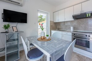 Eine moderne Küche mit weißen Schränken, einem eingebauten Backofen und einem flachbildfernseher an der Wand.