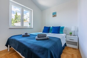 Ein Schlafzimmer mit einem Bett, einem Nachttisch, einem Fenster und einem Bild an der Wand.