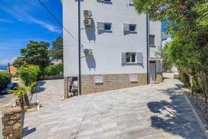 A modern building with multiple air conditioning units, a paved entrance, and a stone base. - Large apartment just 300 metres from the beach with sea views and washing machine (Dramalj)