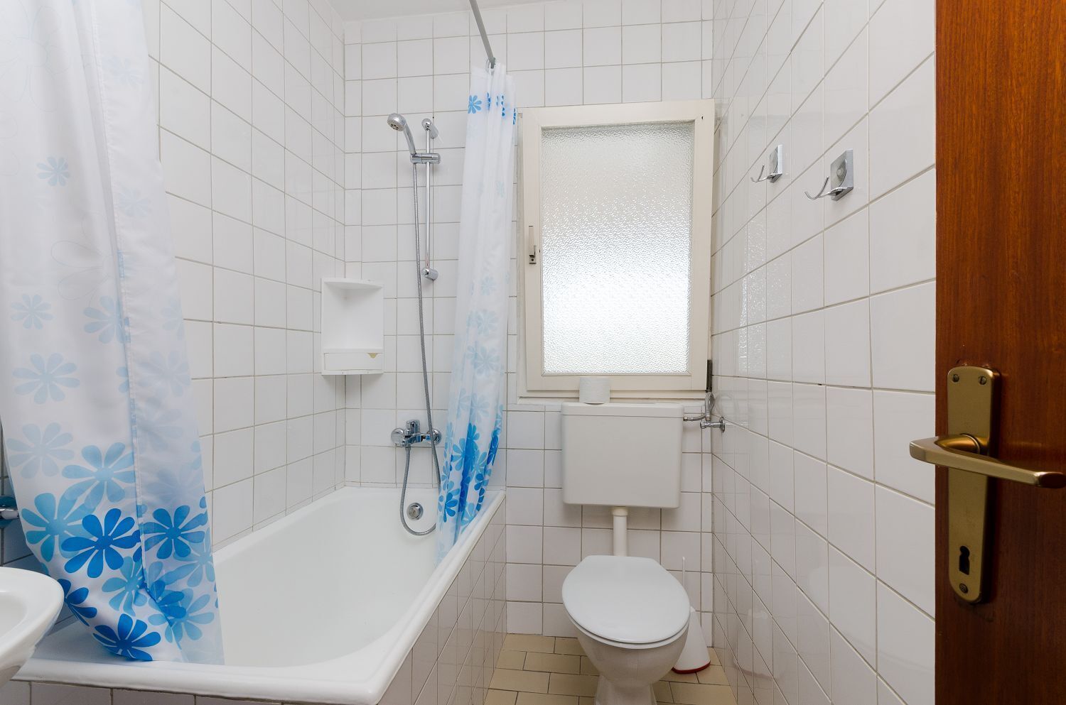 A bathroom with a bathtub, toilet, and a window.