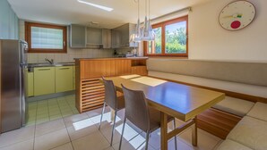 Een compacte keuken met een eethoek, houten kastjes, een inbouwbank en een wandklok.