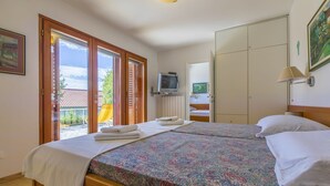 Een hotelkamer met twee bedden, een televisie, een kledingkast en een balkon met een glijbaan.