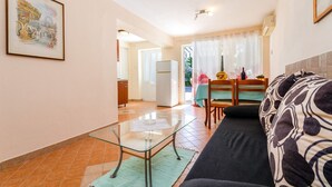Ein modernes Wohnzimmer mit einem Glastisch, einer Couch und einem Essbereich mit Tisch und Stühlen.