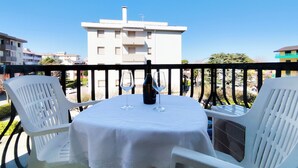 A balcony with a table set for two, two wine glasses, and a bottle of wine. - Comfy Flat With Pool and Balcony (Jesolo)