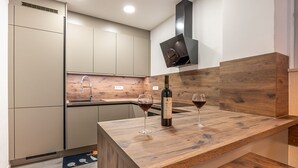 Cocina moderna con encimera de madera, una botella de vino y dos copas de vino.