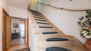 Uma escadaria com corrimão, degraus carpetados e um tapete na base.