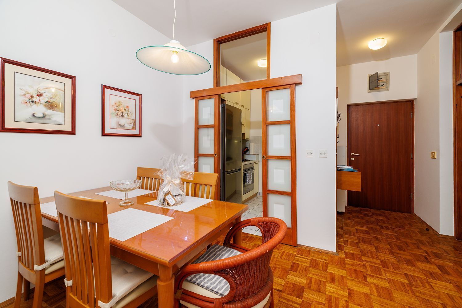 A dining area with a wooden table, chairs, and a hanging light fixture.