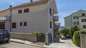 Un bâtiment à deux étages, doté d’un toit en tuiles, d’une entrée fermée par un portail et d’un escalier menant à un balcon.