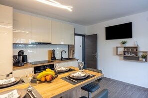 Eine moderne Küche mit einem Holzespeisetisch, einem Einbauofen und einem flachbildschirmfernseher an der Wand.