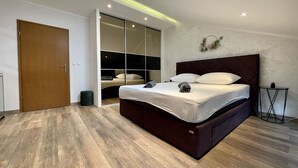 Ein modernes Schlafzimmer mit einem großen Bett, einem eingebauten Kleiderschrank und einem kleinen Nachttisch.