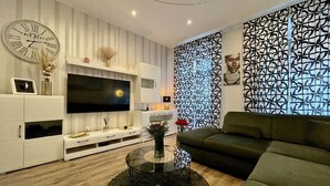 Ein modernes Wohnzimmer mit Flachbildfernseher, einer Couch, einem Couchtisch und einer Wand mit Muster.