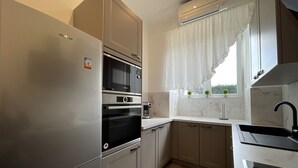 Eine moderne Küche mit Edelstahlgeräten, einem eingebauten Ofen und einem Fenster mit Blick auf Grünflächen.