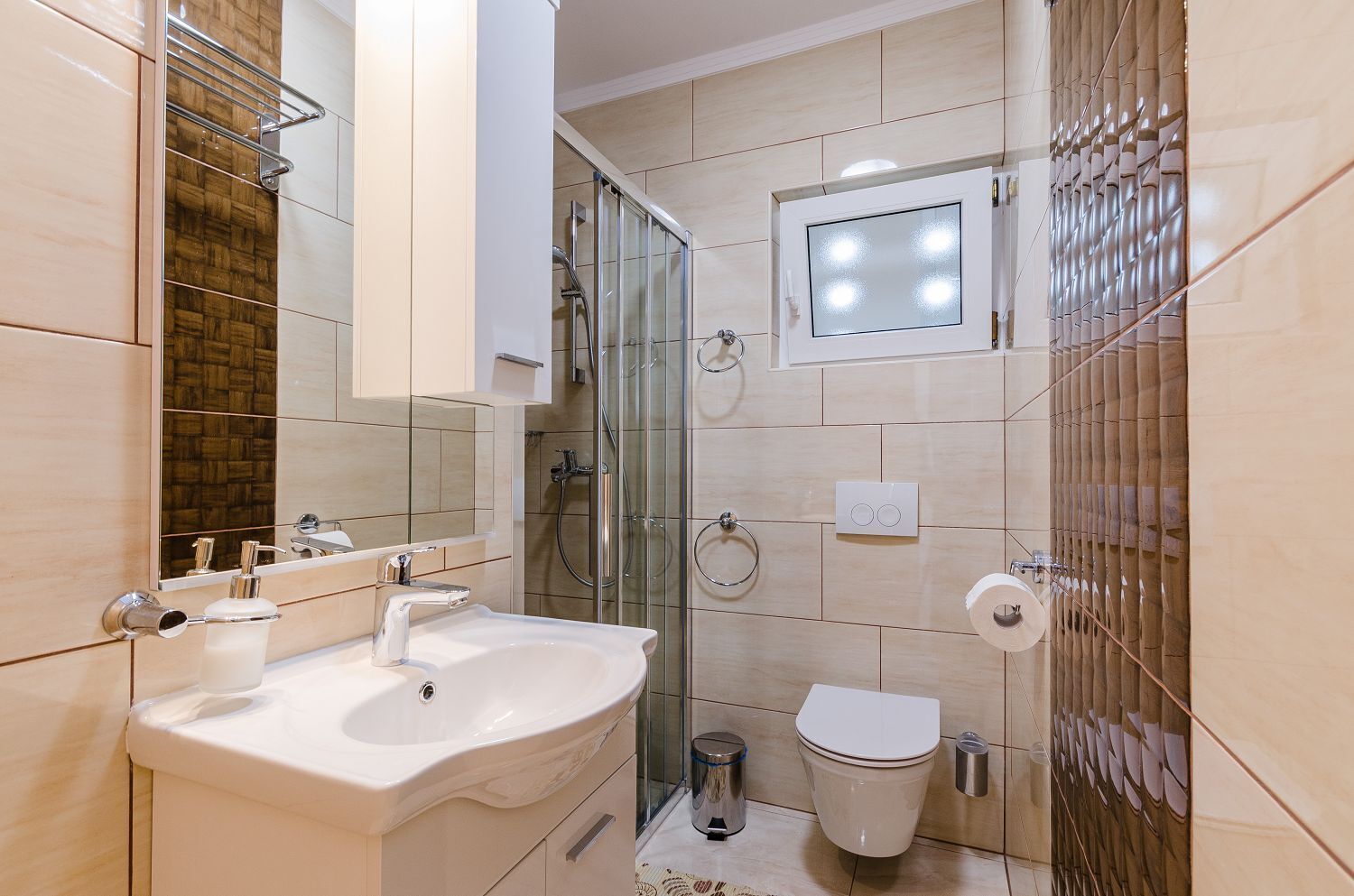 Une salle de bain moderne comprenant un meuble-lavabo, un lavabo, un miroir, une douche et des toilettes.