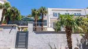 Een gebouw met een witte gevel, een balkon en palmbomen.