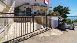 Una propiedad cercada con una escalera que lleva a un balcón, una bandera y vistas al mar.