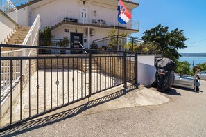 Ein von einer Mauer umgebenes Anwesen mit einer Treppe, die zu einem Balkon führt, einer Flagge und Blick auf das Meer.