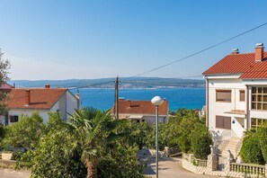 Zona residencial costera con casas, vista despejada al mar y un puente de piedra.