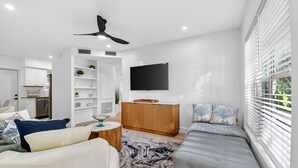 Ein modernes Wohnzimmer mit einer Couch, einem Couchtisch und einem an der Wand befestigten Fernseher.