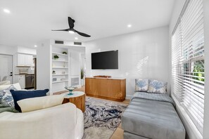 A modern living room with a sofa, a coffee table, and a TV mounted on the wall. - 3 Miles to Atlantic Ave - Turtle Lane (Delray Beach)