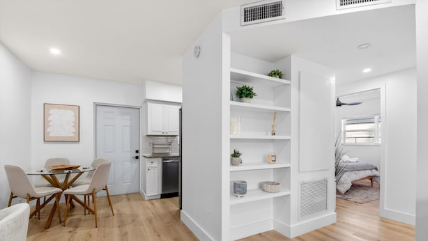 Eine moderne Wohnung mit Essbereich, Küche und einem Schlafzimmer mit eingebauten Regalelementen.