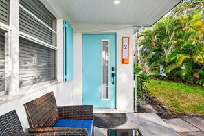 A porch with wicker furniture, a blue door, and a number '2' sign. - 3 Miles to Atlantic Ave - Turtle Lane (Delray Beach)
